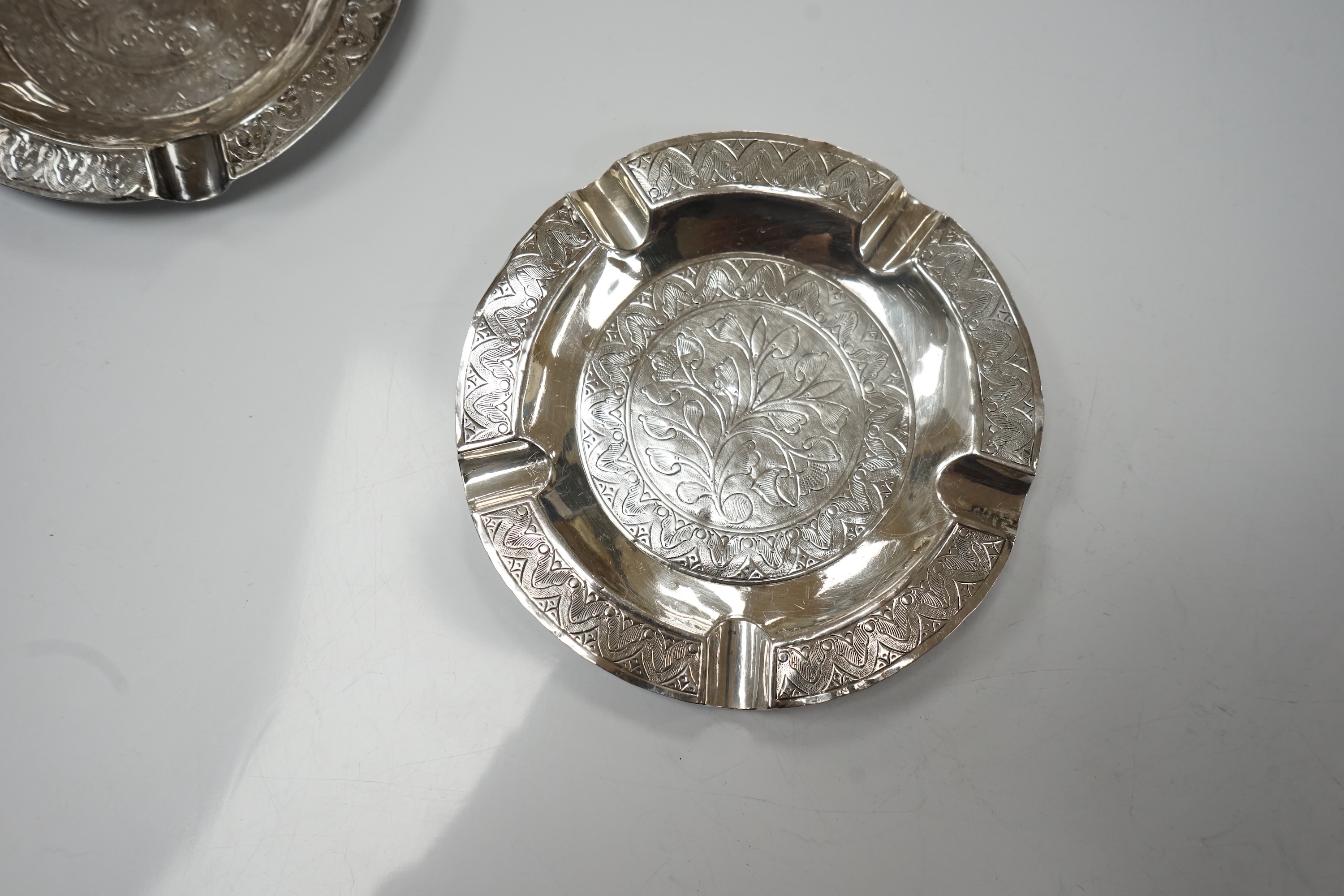 Three Malaysian or Indonesian white metal ashtrays, largest diameter 12.5cm, a similar dish and a bowl. Condition - poor to fair